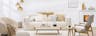 Hyggeliges Wohnzimmer mit cremefarbenem Cordsofa und Kissen, Sesseln im Retro-Stil, einem Strickpouf, Holzmöbeln, Pendelleuchten aus Glas und einem weißen Kamin.