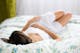Frau im weißen Nachthemd auf einem Bett mit geblümter Bettwäsche liegend