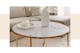 Woonkamer met beige interieur met als middelpunt een salontafel met wit marmeren tafelblad en gouden meubelpoten.