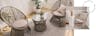Outdoor-Rattanmöbel in einem Indoor-Wohnraum; zwei Rattansessel mit Kissen und ein runder Rattantisch mit Glasplatte, darunter ein grauer Outdoor-Teppich, ringsum viele Grünpflanzen wie Palmen und Sukkulenten