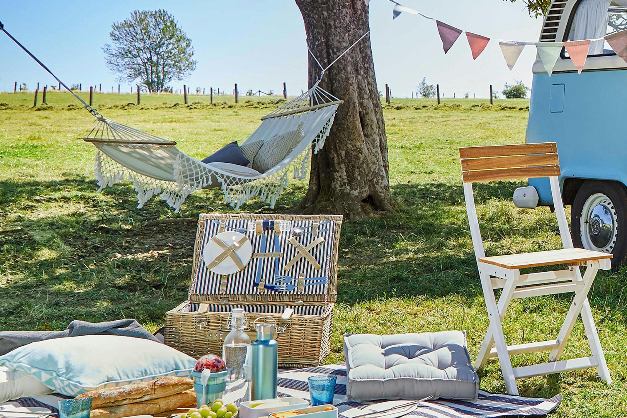 Idyllische Picknick-Setup mit Picknickkorb, Hängematte, Kissen und Wimpelkette