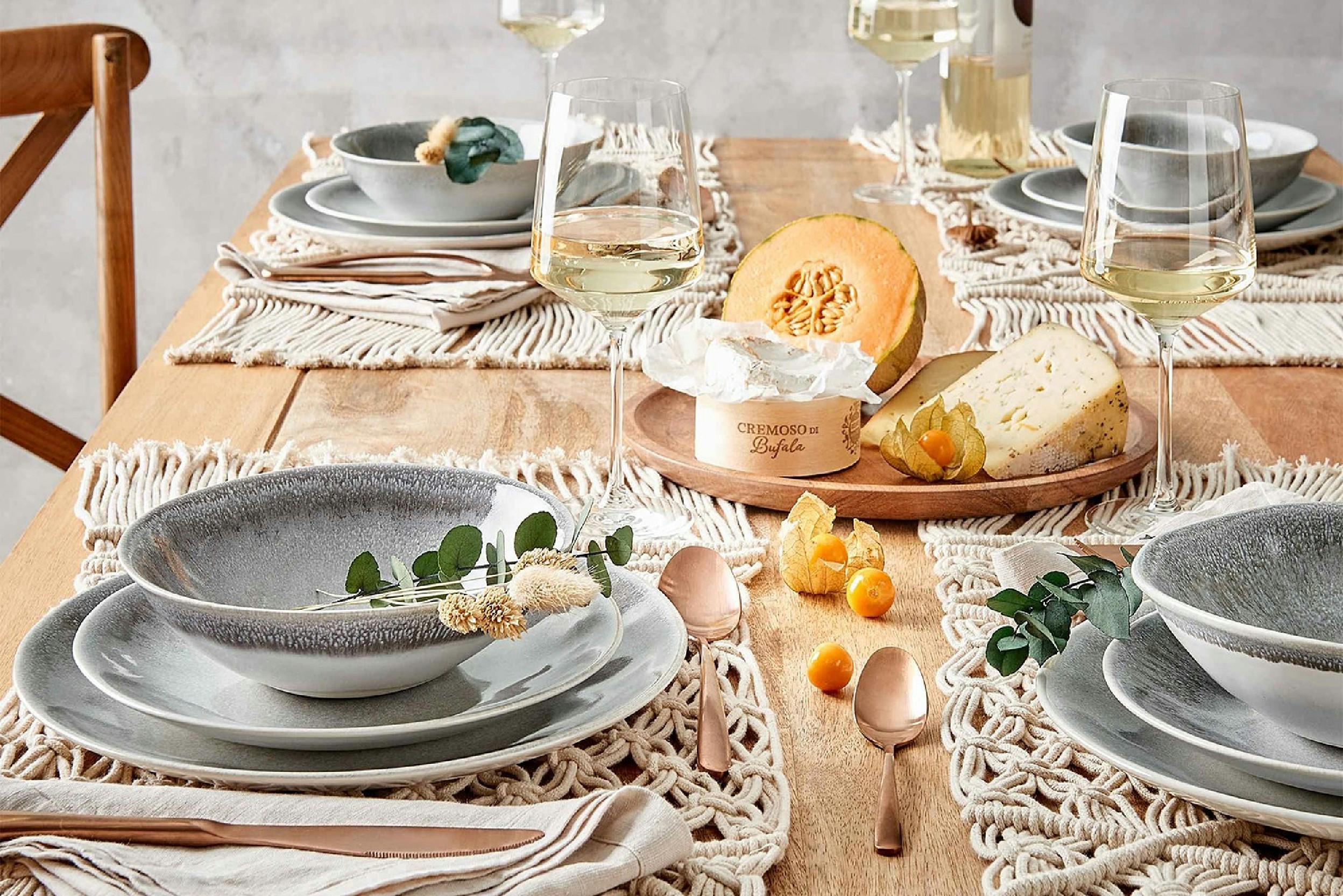 Tisch schön aufgedeckt mit Macramé Tischset, verschiedene Teller und Schalen, Gläser, Käse und Melone.