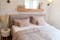 Bett und Bettwäsche in Altrosa kombiniert mit Pampasgras, Wandleuchten und einem rahmenlosen Spiegel