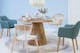 Runder Tisch mit hellen Holzsträngen, der von unterschiedlichen Stühlen im Skandi-Stil umgeben und mit Keramikgeschirr in zarten Pastelltönen sowie einem Trockenblumenstrauß gedeckt ist.