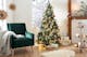 Petrolkleurige fluwelen fauteuil met lichtgrijze bekleding, daarnaast een feestelijk versierde kerstboom met veel cadeautjes en kerstversiering (voornamelijk in zilver, goud en lichtblauw)