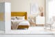 Lit capitonné de velours jaune moutarde avec boutons Chesterfield dans une chambre de style scandinave équipée de textiles douillets