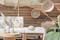Outdoor-Loungemöbel der Serie LEXI by BUTLERS aus hellem Akazienholz mit weissen Polstern, dazu ein passender Tisch dekoriert mit weissen Vasen, ein weisser Sonnenschirm mit Fransen, ein Outdoor-Teppich und Pouf aus Jute sowie Wanddeko, Pflanzenkorb und Windlicht in Flechtoptik.