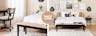 Una camera da letto arredata con letto, comò e scrittoio del marchio esclusivo kollected di home24. Il tutto abbinato a tessili, quadri, uno specchio da parete, due lampade nere di rattan e oggetti decorativi.
