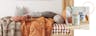 Kinderbett aus Holz mit einer Hausform am Kopfende sowie Bettwäsche und Kuscheltiere in erdigen Farbtönen und einem Bild mit niedlichem Elefanten im Hintergrund; daneben zwei Dosen von BUTLERS mit niedlichen Tier-Prints.