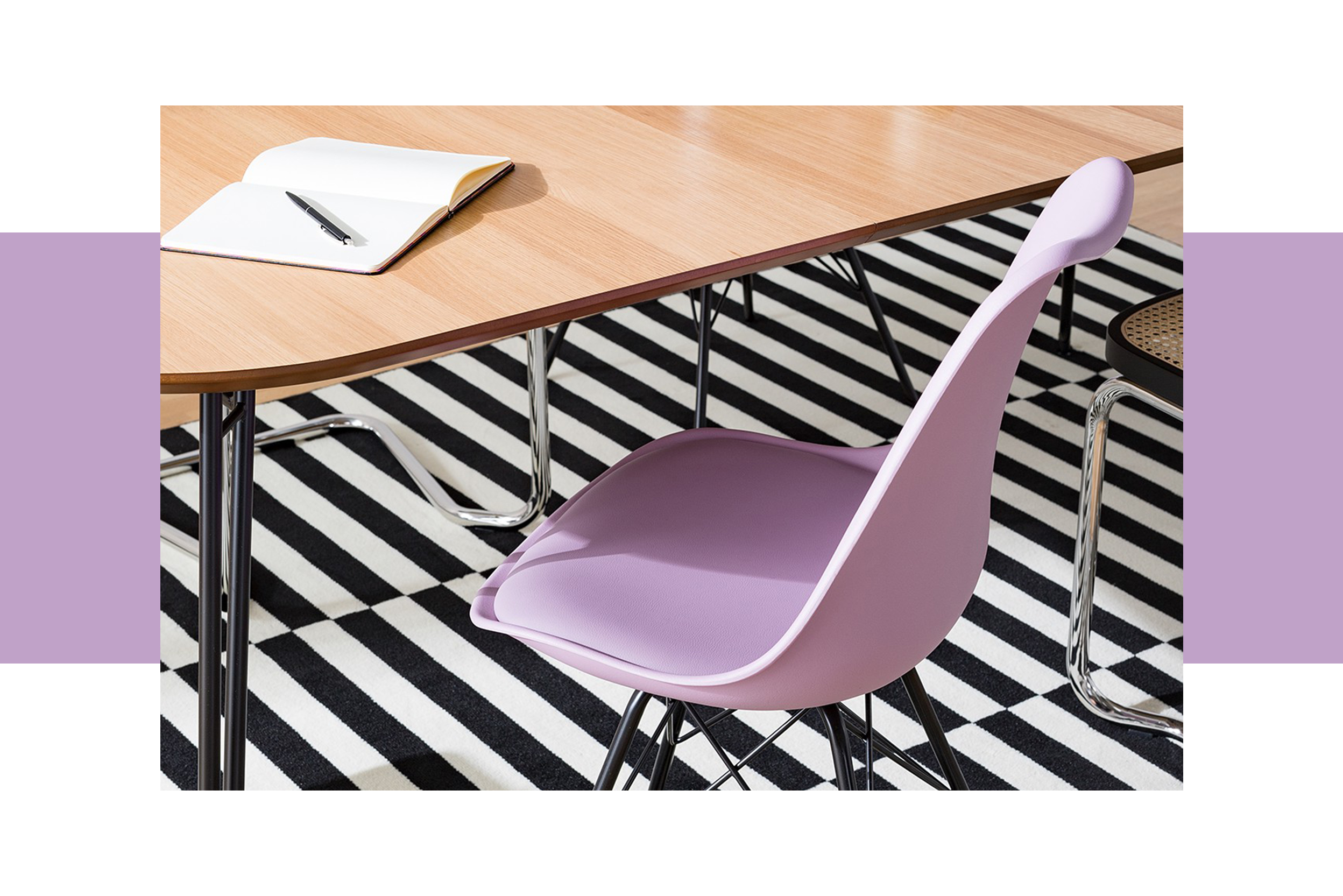 Ein Esszimmerstuhl in hellem Fliederton sowie ein Stuhl mit Wiener Geflecht vor einem Esstisch aus Holz auf einem schwarz-weiß gestreiften Teppich.