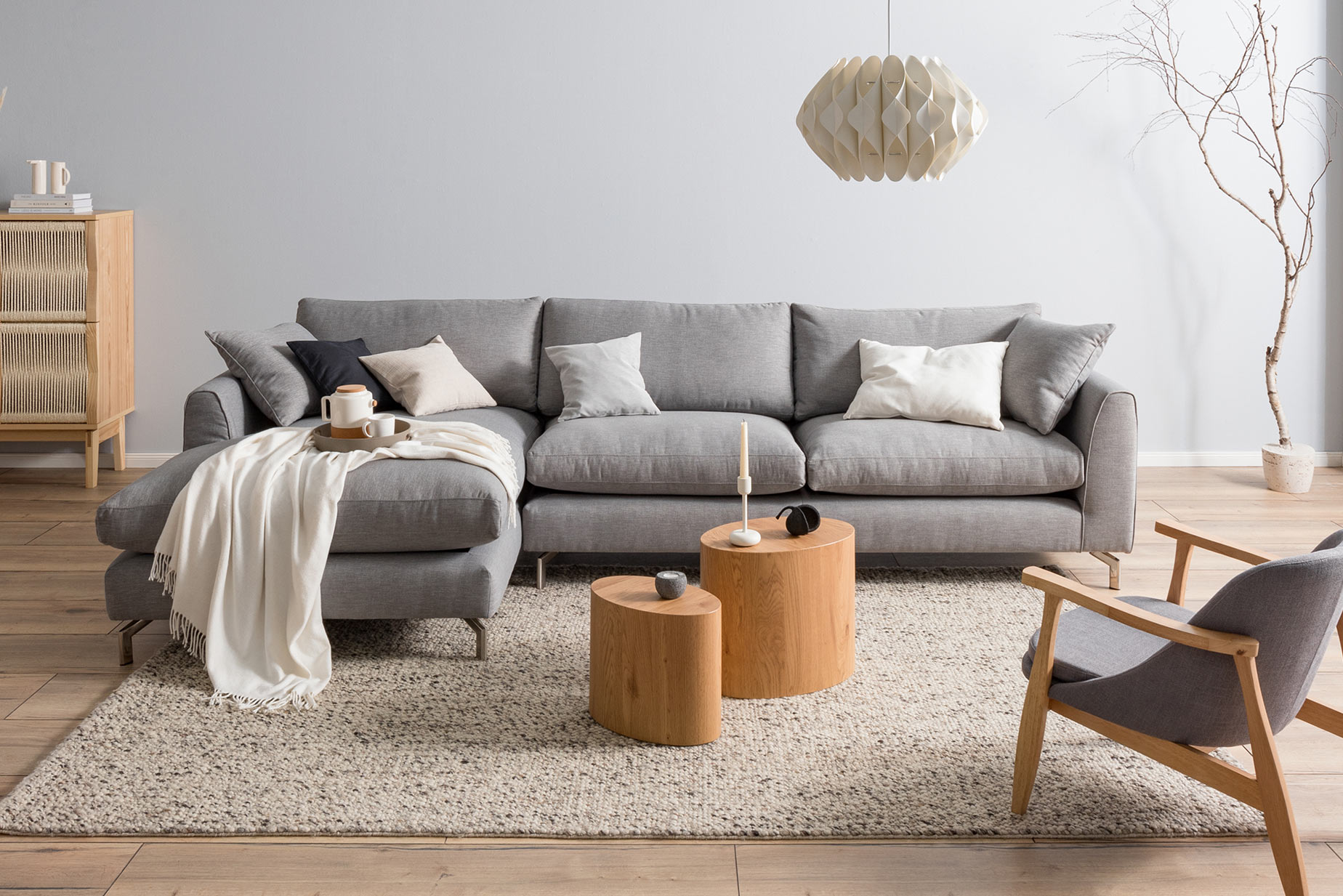 Graues Sofa mit hellen Holzmöbeln im Japandi-Stil