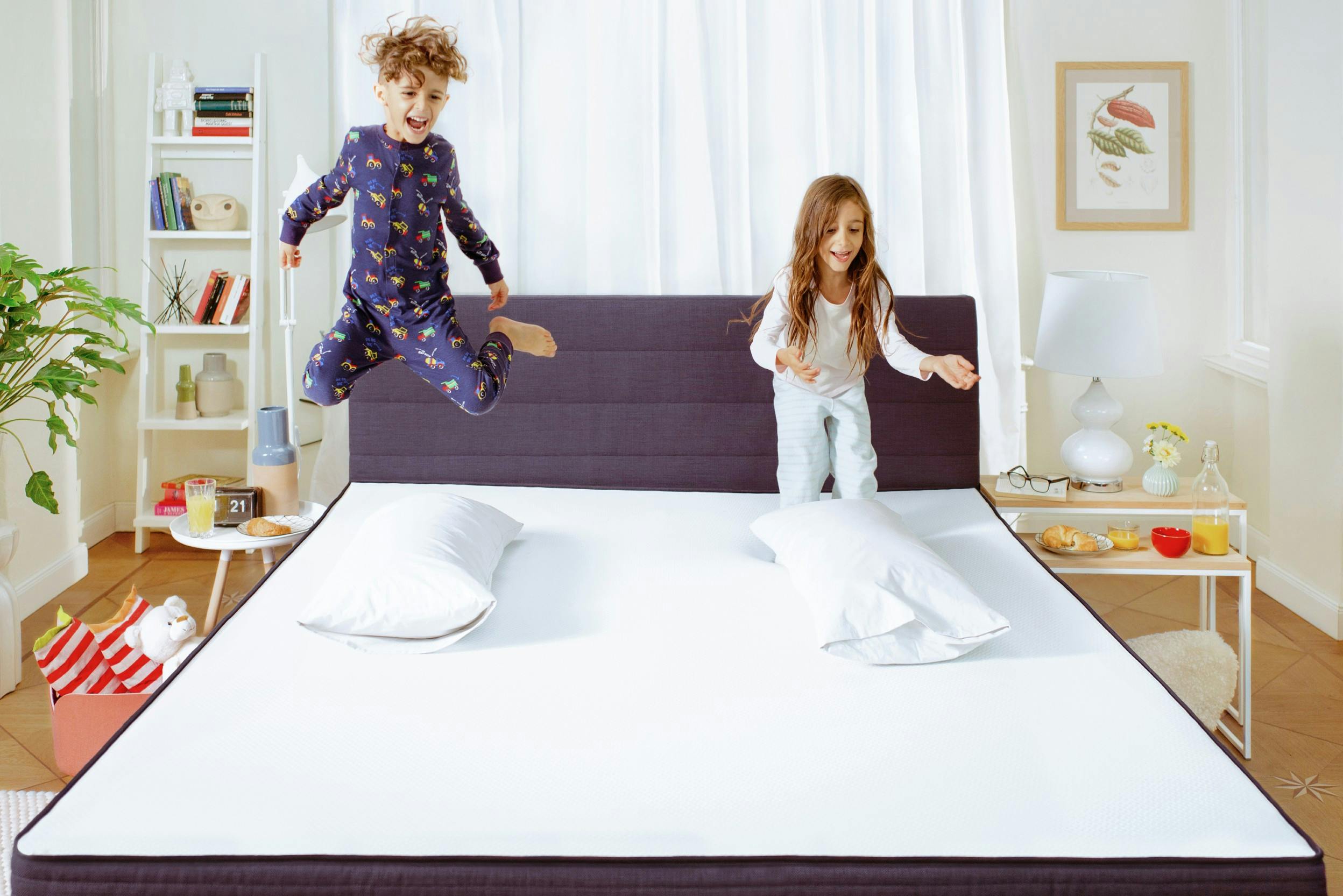 Zwei Kinder hüpfen ausgelassen auf einem Bett