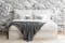 Lit boxspring blanc KINX par Studio Copenhagen, une marque exclusive home24, devant un mur avec un papier peint imitation marbre, table d'appoint, suspension et vêtements posés sur une chaise cannée.