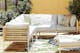 Modulare Loungemöbel für Terrasse, Garten und Balkon aus Teakholz mit einem Gestell aus Edelstahl, hellgrauen Polstern und kombiniert mit Outdoor-Teppich und Kissen in Grün