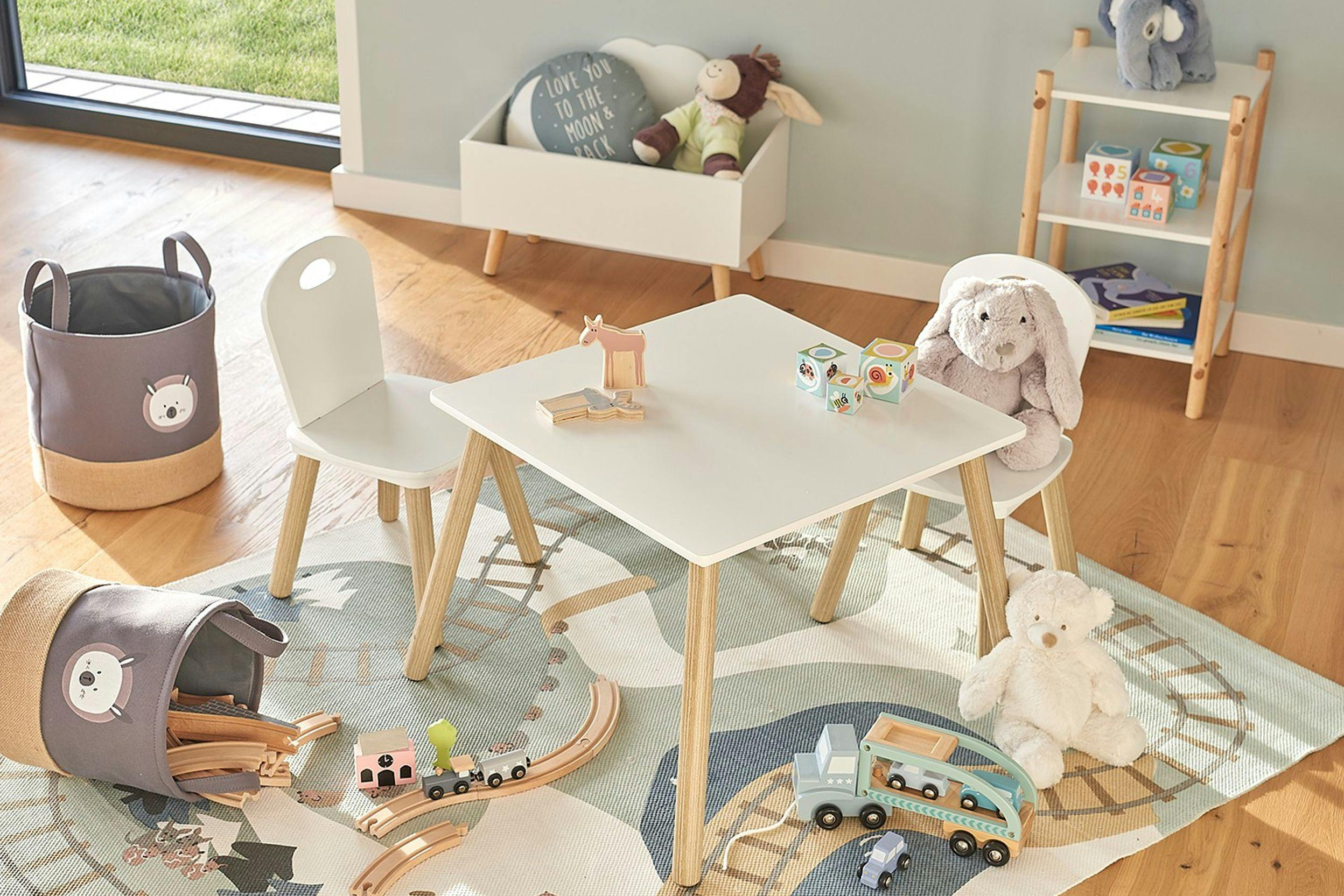 Photo d'une chambre d'enfants avec jouets sur le sol, et différents accessoires de rangements, comme des paniers, et un coffre à jouets