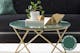Aufsehenerregende Oberflächenstruktur einer Tischplatte aus grünem Marmor, dekoriert mit goldenen Objekten und einer Grünpflanze