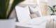 Lit gris clair avec linge de lit blanc, lampe blanche et plantes décoratives 