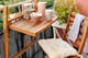 Petit balcon verdoyant à l'aspect chaleureux grâce à des meubles pliants en bois et un tapis extérieur BUTLERS dans les tons beiges.