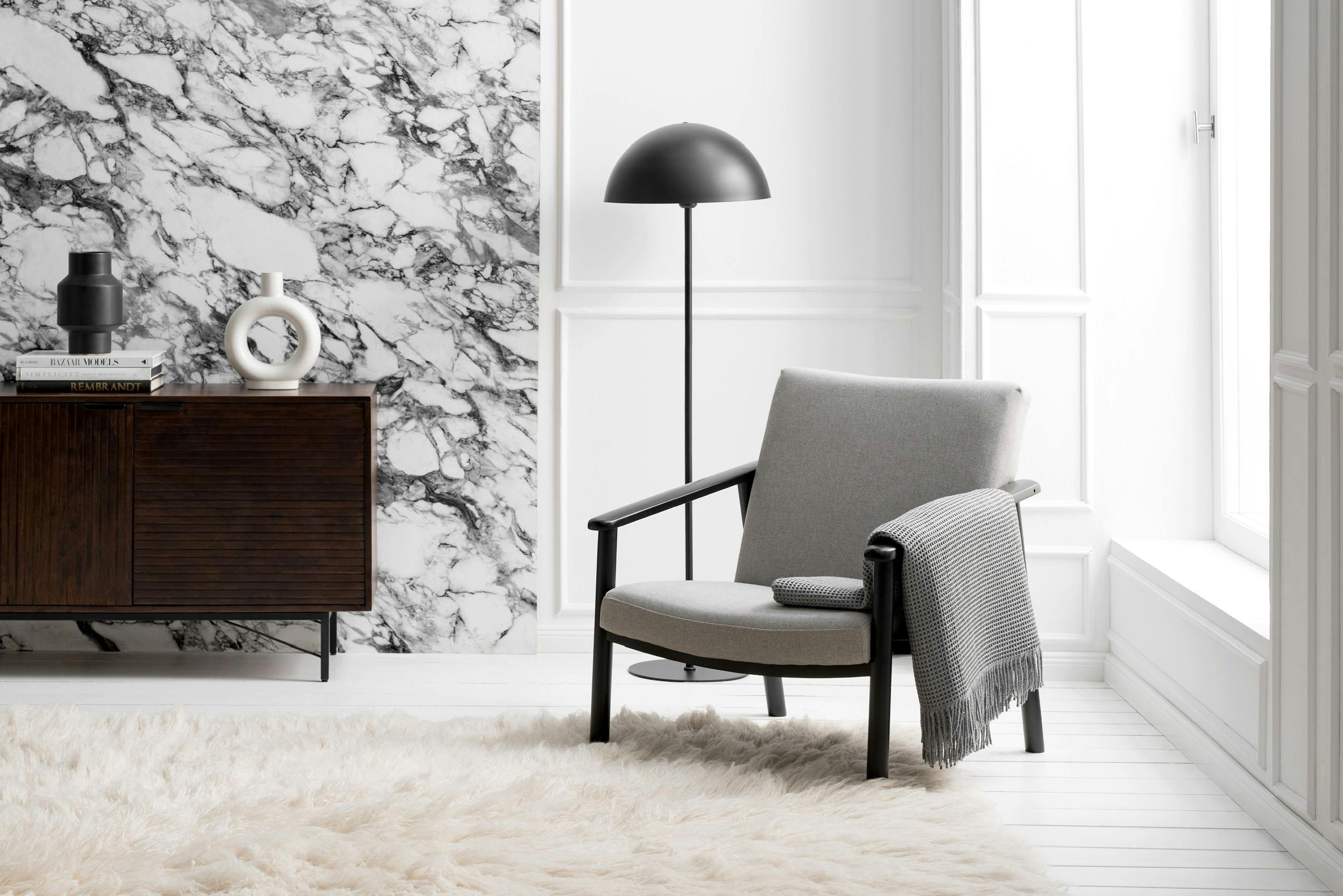 Grauer Sessel mit Stehlampe dahinter in modernem, minimalistischem Design