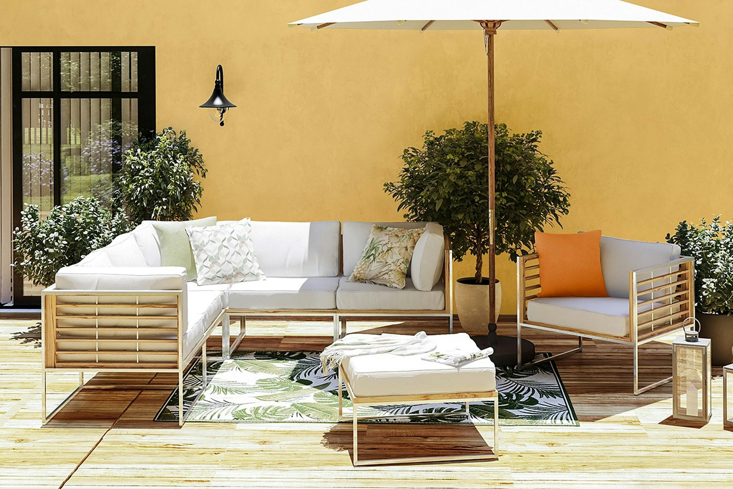 Gartenlounge mit weissen Polstern mit Sonnenschirm vor gelber Hauswand