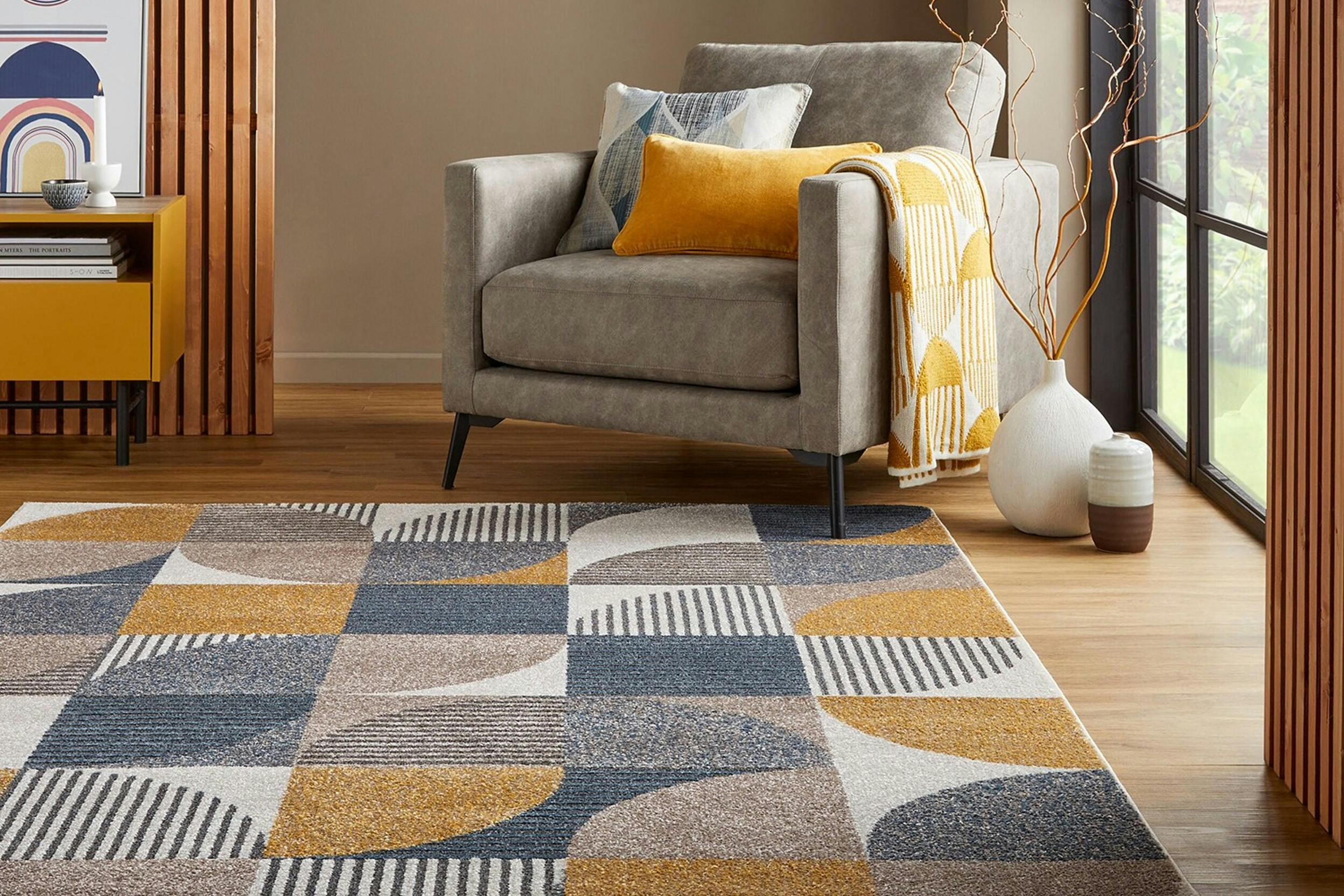 Grauer, blauer und gelber geometrischer Teppich vor einem Sessel