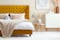 Schlafzimmer im Skandi-Stil mit Paravent vor Samtbett in Senfgelb