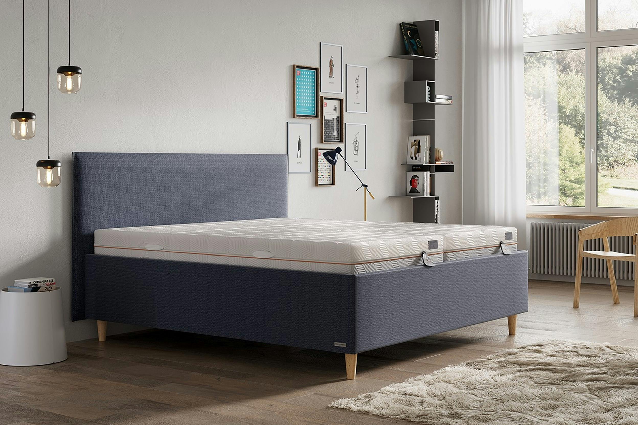 Graues Polsterbett mit zwei Matratzen in einem modern eingerichtetem Zimmer