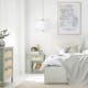 Schlafzimmer mit weißem Boxspringbett und heller Bettwäsche sowie einem Nachttisch und dem passenden Highboard in Mintgrün und Applikationen in Wiener Geflecht