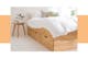 Stauraumbett aus hellem Holz mit 3 Schubkästen, weißer Bettwäsche und weißen Pendellampen über dem filigranen Nachttisch.
