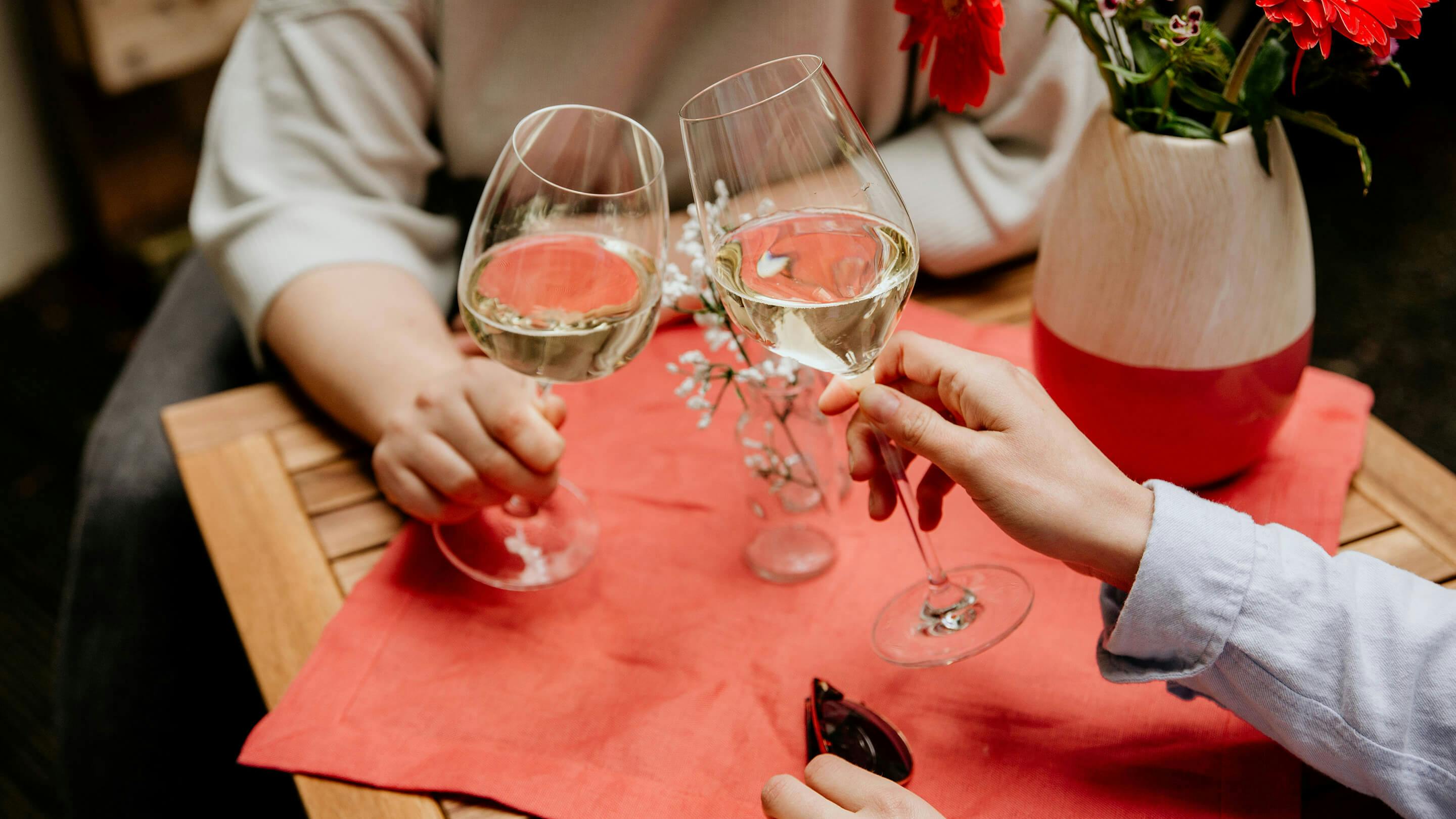Halb gefüllte Weissweingläser, rechteckiger Gartentisch, rotes Tischset, zweifarbige Vase (Marke: Butlers).
