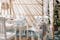 Gazebo in bambù con tende bianche e mobili da esterno di legno con cuscini carta da zucchero e coperta grigio scuro e lampada intrecciata in materiali naturali.