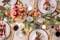 Festlich gedeckter Tisch mit traditioneller Weihnachtsdeo in Rot, Weiß sowie mit Tannengrün, goldenem Geschirr, Lichter- und Kerzenglanz.