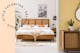 Schlafzimmer im Boho-Style mit gelber Wand und Möbeln aus Wiener Geflecht wie einem Bett mit extravagantem Kopfteil; Weißes Boxspringbett mit gepolstertem, hohem Kopfteil, welches mit Kissen und Makramee dekoriert ist