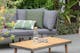 Modulare Loungemöbel für den Garten aus Akazienholz mit grauen Polstern; hier vor grünem Pflanzen zu sehen