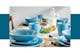 Frühstückstisch aus markantem Holz mit türkisenem Keramikgeschirr bestehend aus Tellern, Schüssel und Tassen sowie goldenem Besteck.