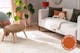 Salon cosy avec un tapis beige clair aux motifs losanges discrets ; à côté, un tapis rond avec un motif floral noir et blanc.