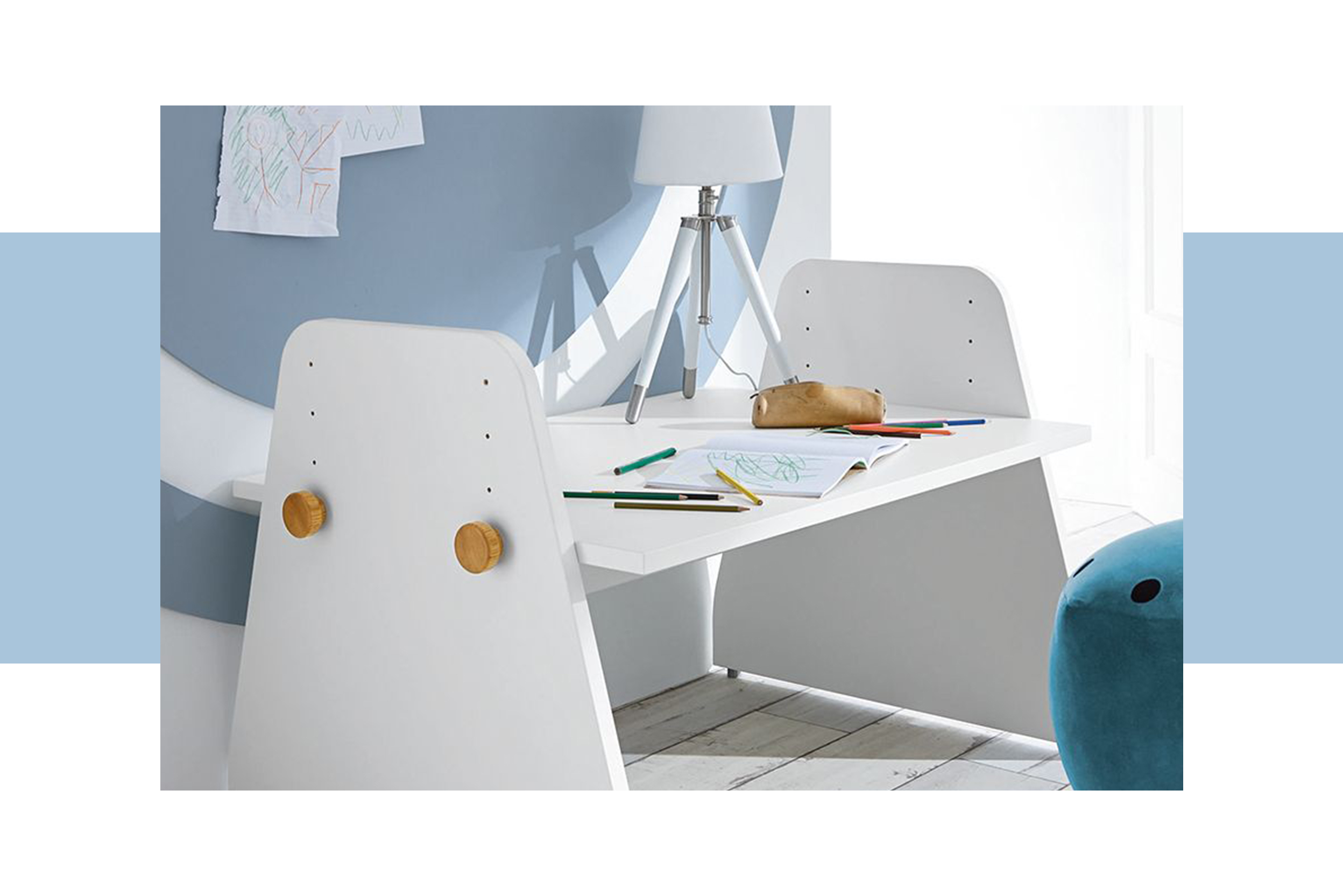 Arbeitsecke im Kinderzimmer mit einem weißem Kinderschreibtisch, der vor einer hellblauen Wand platziert ist und einem offenen Wandregal
