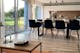 Table basse de style industriel en bois et métal noir sur un tapis couleur rouille, table de salle à manger et cuisine ouverte en arrière plan.