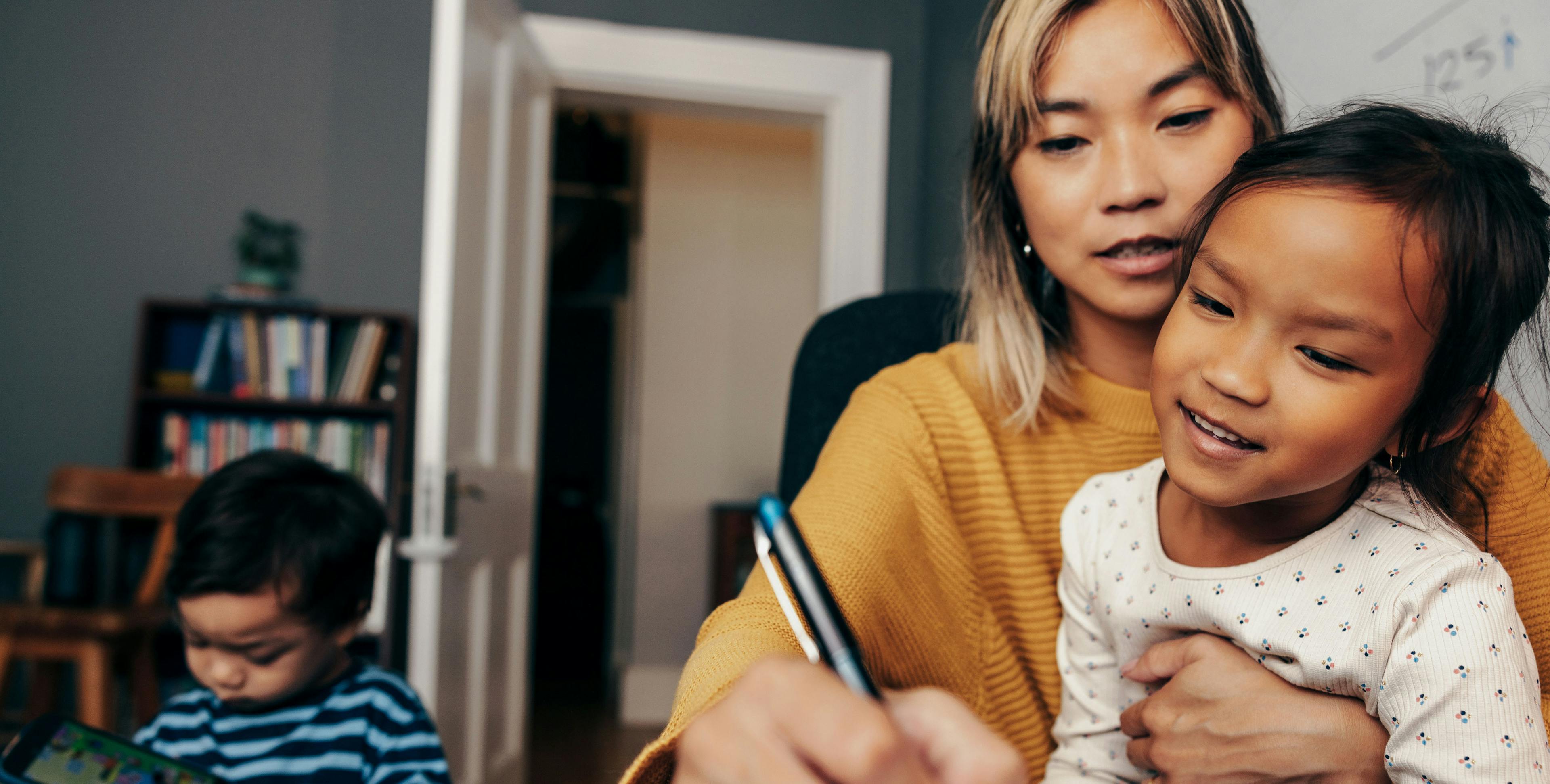 Mother writing with a pen while holding a child