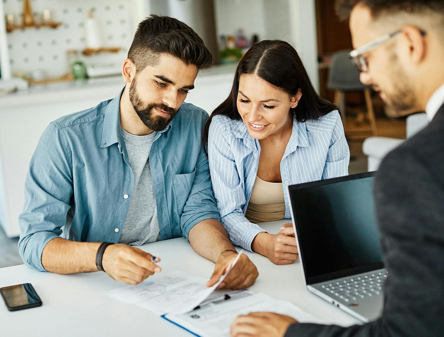 Man and woman looking at forms while another man in a suit is on the other side of the table