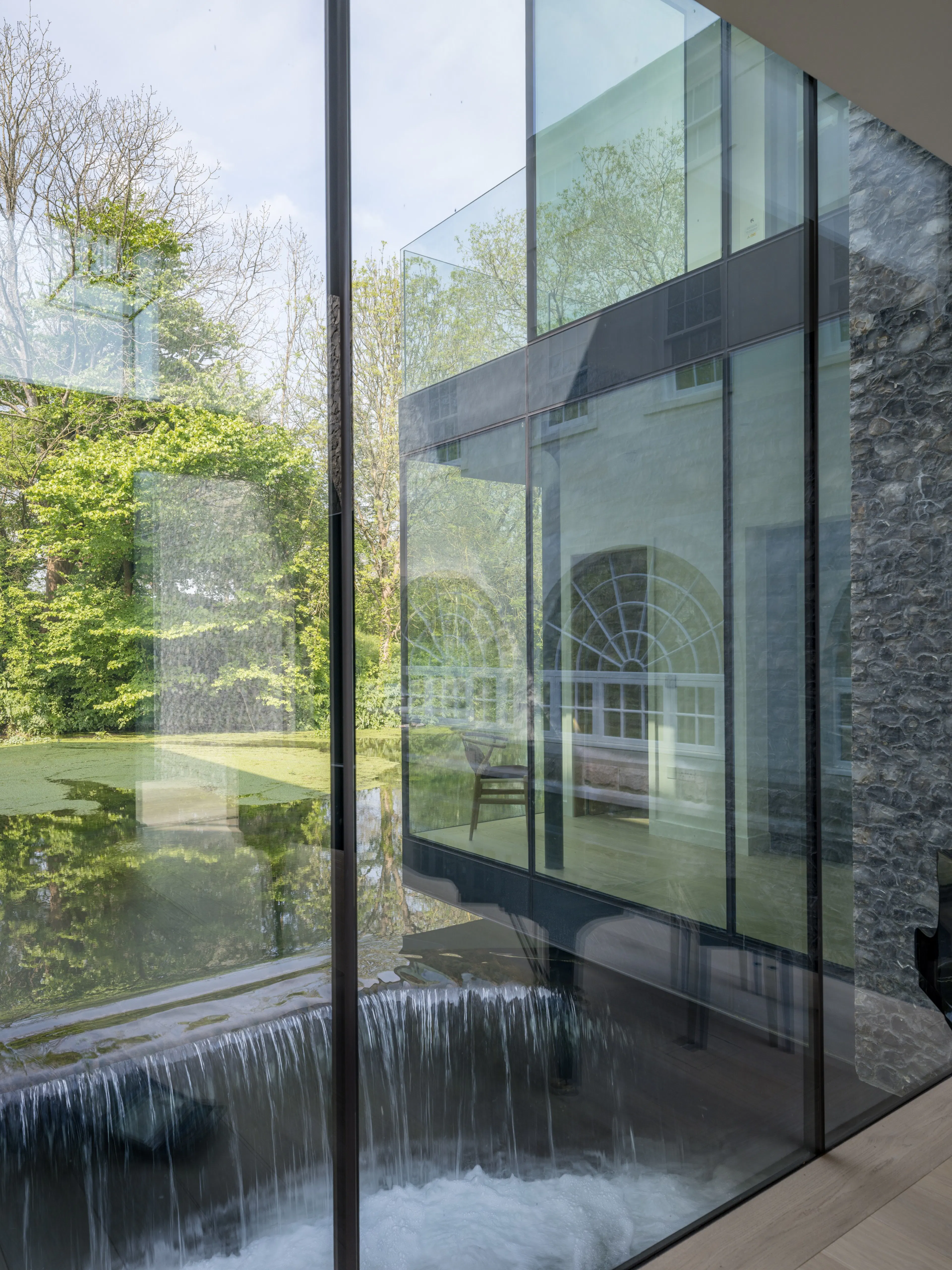 The mill race flowing beneath the glass wing, seen through its glazed corner