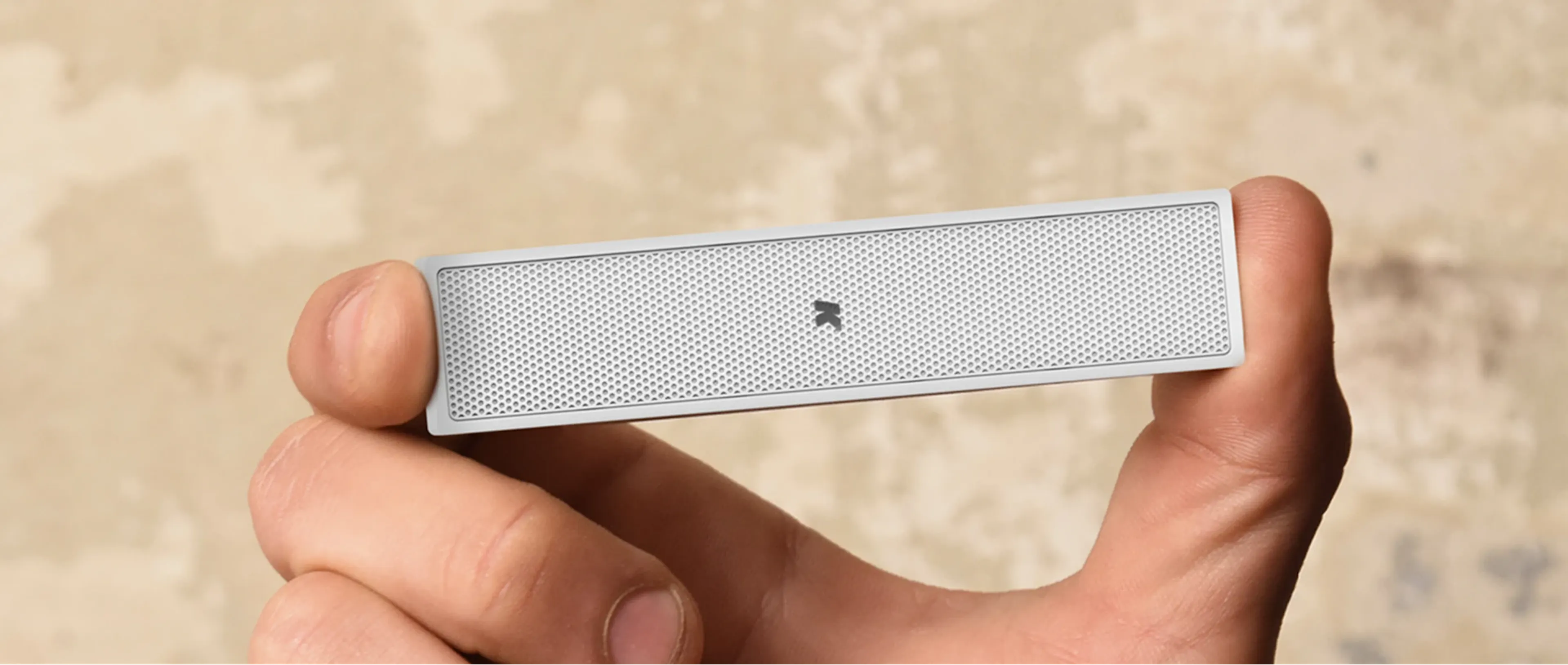 K-array Lyzard speaker held flat between thumb and fingertips