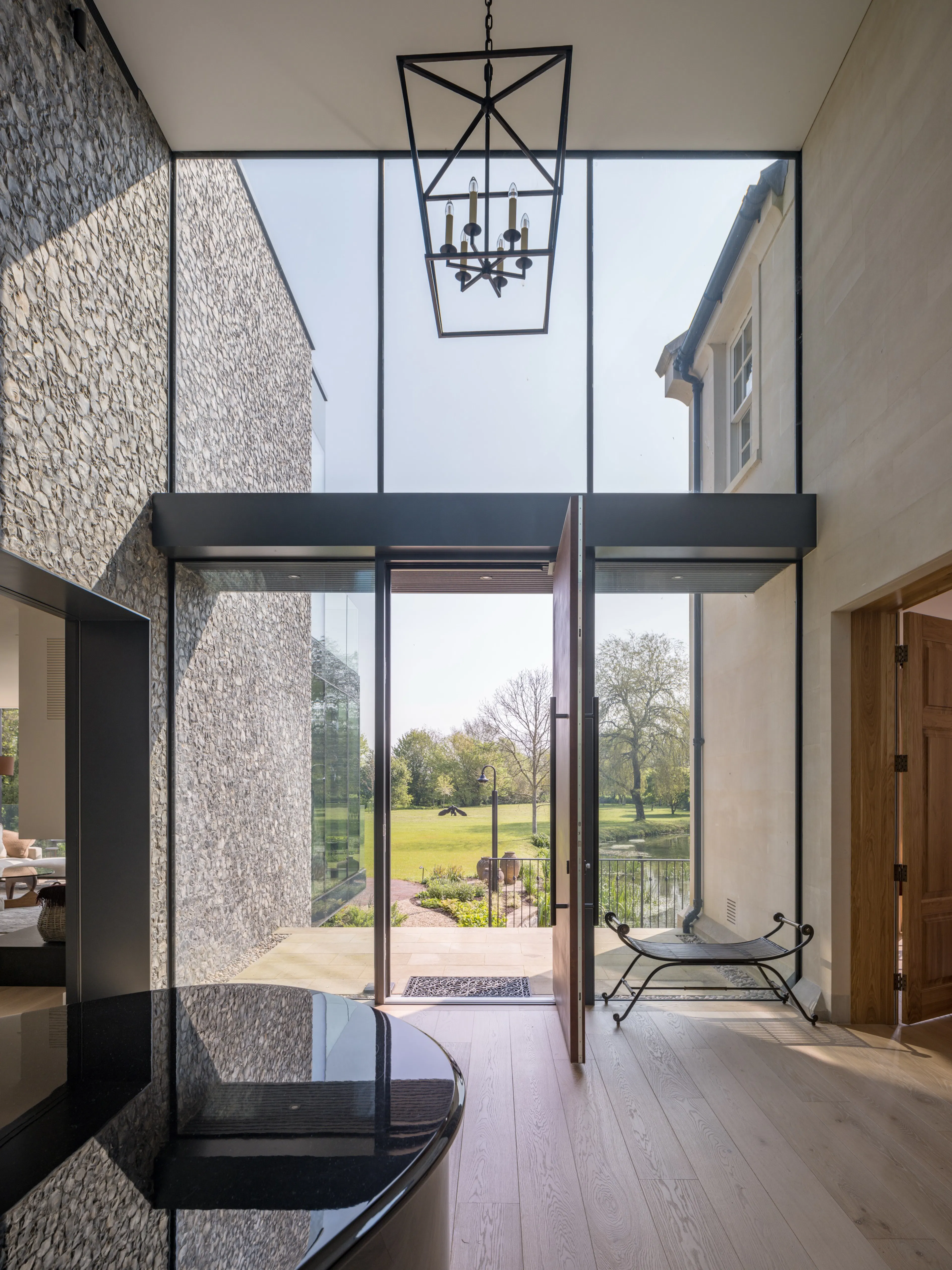 Double-height entrance hall with a flint wall, lantern pendant and the front door open to the garden