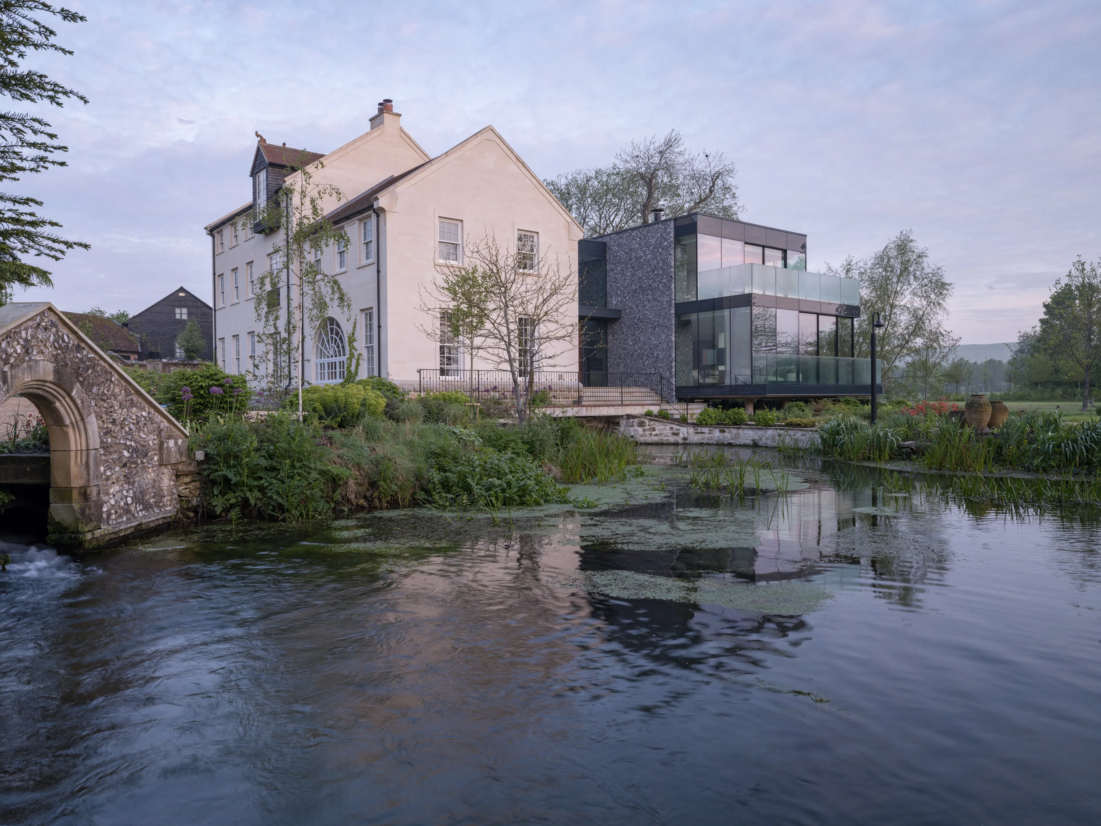 The restored mill house, its stone bridge and the new glass wing beside the river