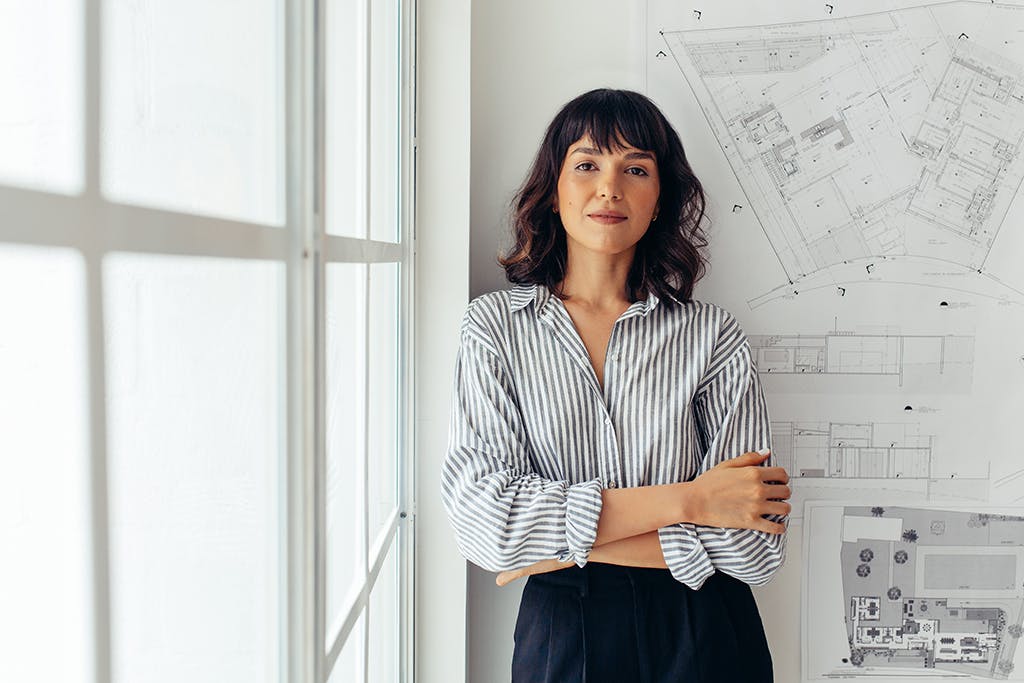 Female architect standing on a wall with floor plans