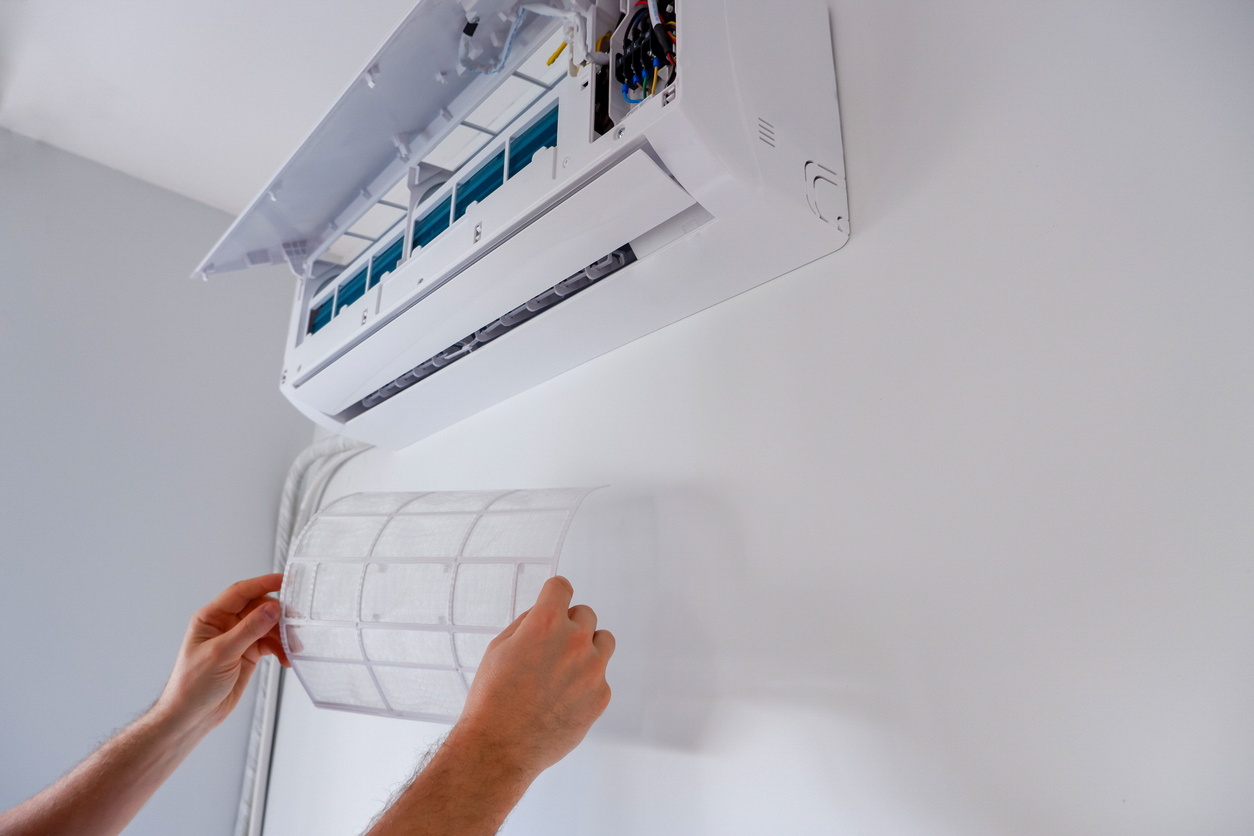 Une personne remet en place le filtre propre de son unité intérieure de climatisation