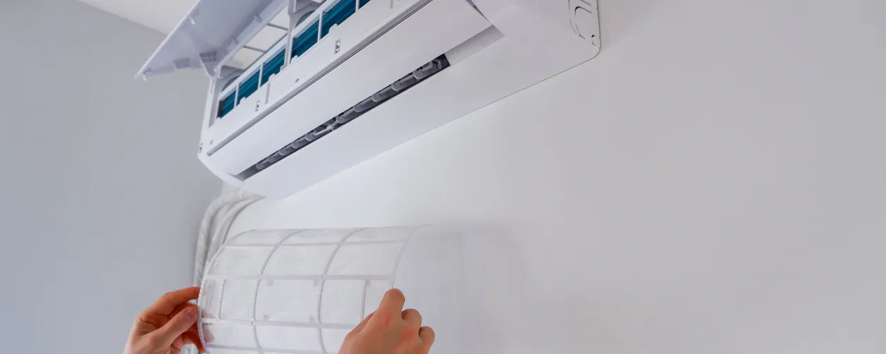 Une personne remet en place le filtre propre de son unité intérieure de climatisation