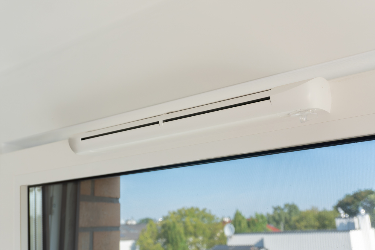 Gros plan sur une grille d'aération de fenêtre installée sur une menuiserie PVC blanche