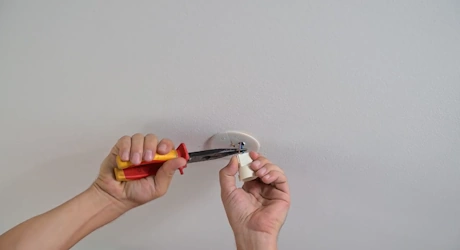Mains vissant un support de plafonnier rond avec tournevis