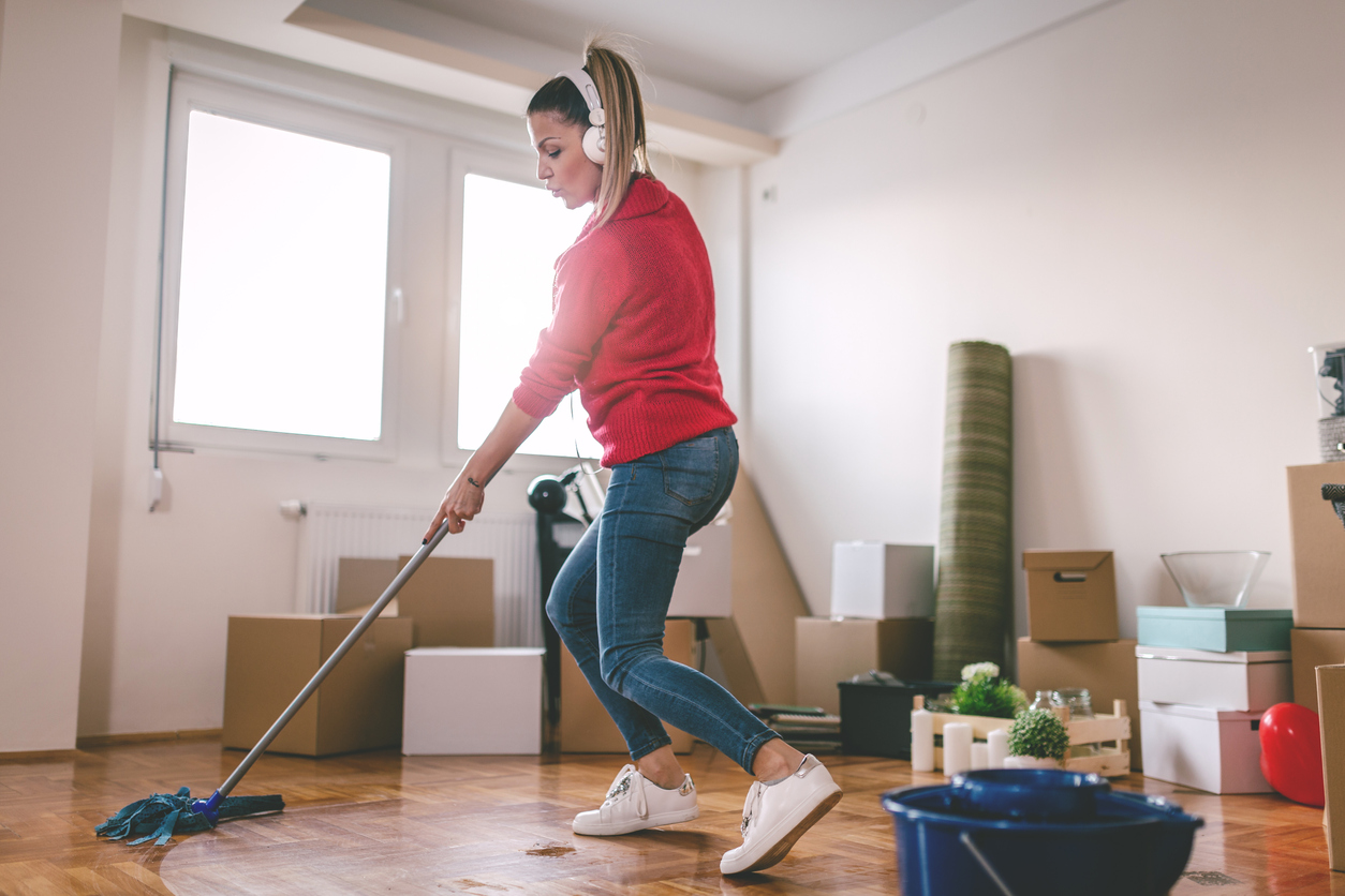Femme avec casque audio nettoyant un parquet avec une serpillière